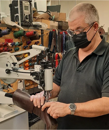 Cordonnerie : artisan réparant une botte en cuir.