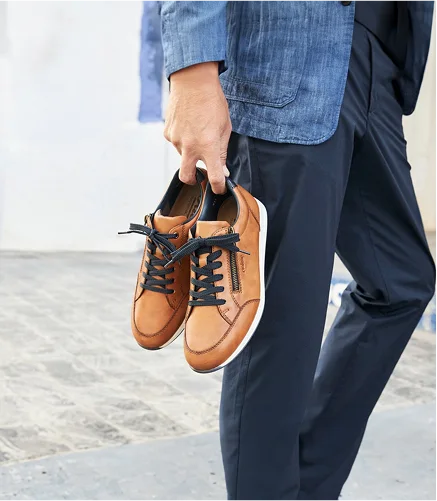 Homme tenant des chaussures marron élégantes.