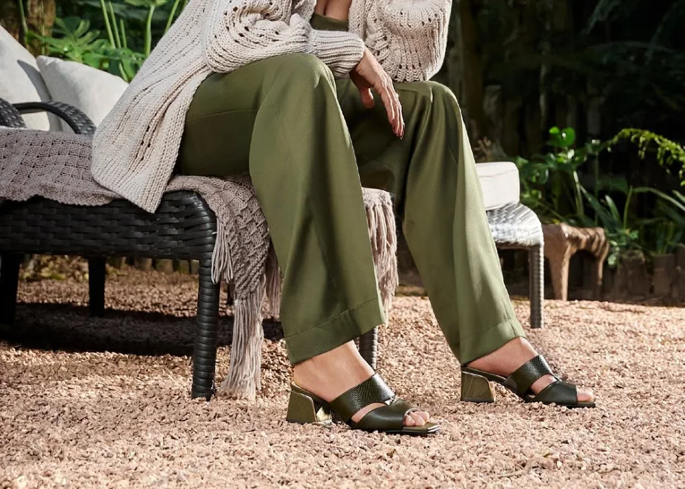 Personne assise, portant sandales et pantalon vert.