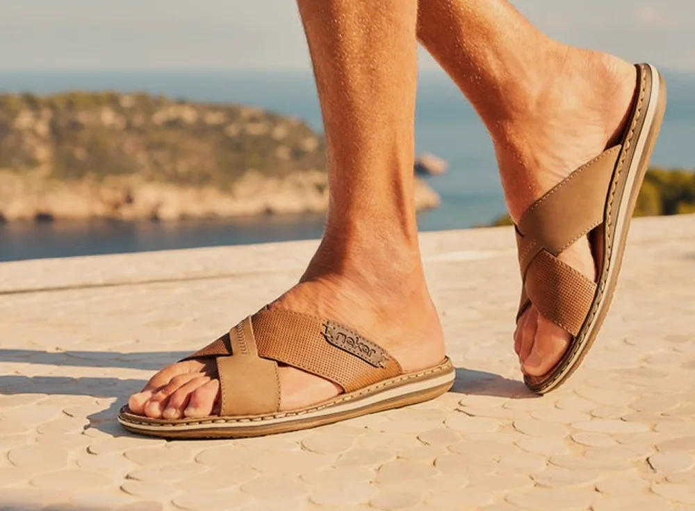 Sandales en cuir sur fond de paysage côtier.